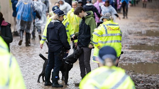 Police officers and a drug detection dog walk among festivalgoers at the entrance of Splendour in the Grass 2022.