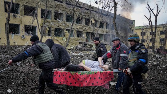 Ukrainian emergency employees and volunteers carry an injured pregnant woman from a maternity hospital damaged by shelling in Mariupol.