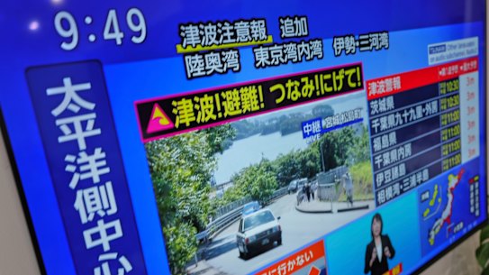 A tsunami warning is displayed on a television in Yokohama, near Tokyo, on Wednesday,