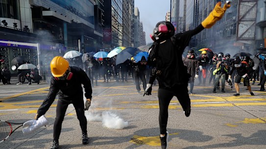Protesters throw the tear gas canisters fired by riot policemen during a rally in Hong Kong.