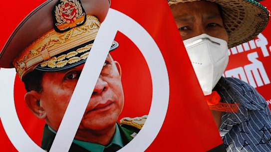 A protester holds a placard with the face of Myanmar’s commander in chief, Senior General Min Aung Hlaing during an anti-coup rally in front of the Myanmar Economic Bank in Mandalay.