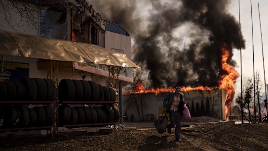 A man recovers items from a burning shop following a Russian attack in Kharkiv.