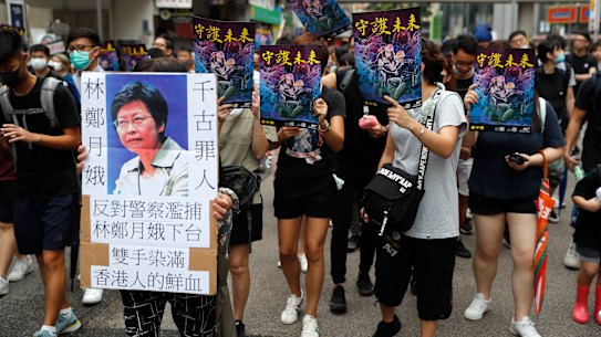 A protester holds a sign that reads: "Carrie Lam condemned by history," as they march through the streets of Mong Kok.