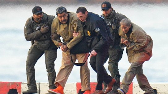 Nicolas Maduro and his wife, Cilia Flores (right) are seen handcuffed at the heliport before their transfer to court.