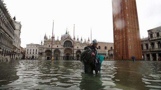 A woman carries her daughter in a flooded St. Mark's Square in Venice on Tuesday.
