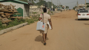 Deborah Sebi carrying immunisations in a refrigerated box on her way to set up the mobile clinic in Teshie, a fishing village near Accra, Ghana.
