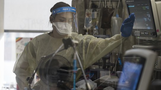A healthcare worker treats a patient inside a negative pressure room in the COVID-19 intensive care unit (ICU) at Freeman Hospital West in Joplin, Missouri.