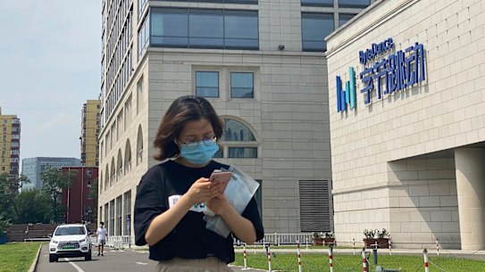 A woman uses her phone as she passes by the ByteDance headquarters in Beijing, China.