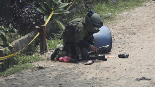 A member of the police bomb disposal squad inspects a suspicious package found inside a garbage, that they later destroyed, in Bekasi on the outskirts of Jakarta, Indonesia, on Monday.