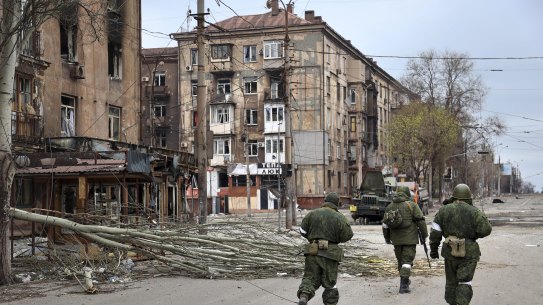 Servicemen of the militia from the Donetsk People’s Republic walk past damaged apartment buildings near the Mariupol plant.