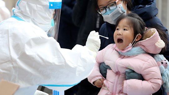 A worker in a protective suit takes a swab from a child for a coronavirus test in Shijiazhuang in China’s Hebei Province last year. 