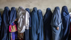 Afghan women wait to receive food rations distributed by a humanitarian aid group, in KabuL