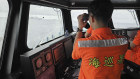 A Taiwan Coast Guard member monitor Chinese navy vessel operating near the Pengjia Islet north of Taiwan on Thursday.
