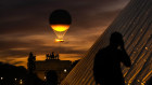 The Olympic cauldron and its balloon, suspended above the Paris sky.