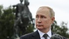 Vladimir Putin stands in front of a statue of Peter the Great in St Petersburg.