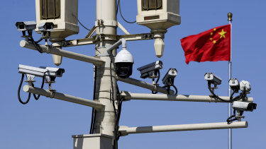 A Chinese national flag flutters near the surveillance cameras in Tiananmen Square in Beijing on Friday. Chinese Premier Li Keqiang denied Beijing tells its companies to spy abroad.