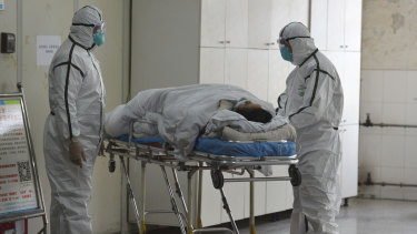 Medical workers in protective suits move a coronavirus patient into an isolation ward at the Second People's Hospital in Fuyang in central China's Anhui Province.