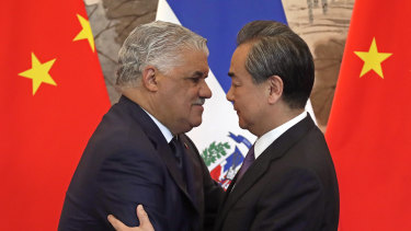 Dominican Foreign Minister Miguel Vargas, left, hugs  Chinese Foreign Minister Wang Yi after they signed the joint communique at the Diaoyutai State Guesthouse in Beijing, on Tuesday.