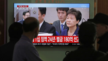 People watch a TV screen showing file footage of former South Korean president Park Geun-hye during a news program on Friday.