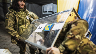Ukrainian government soldiers, members of the local election commission, open a ballot box in a tent using as a polling station.