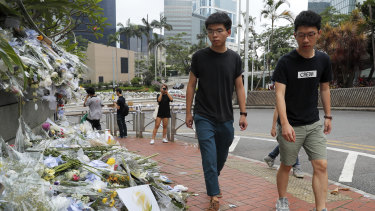 Pro-democracy activist Joshua Wong, left, is accompanied by Nathan Law as they visit a makeshift memorial to a protester who fell to his death when hanging a banner.