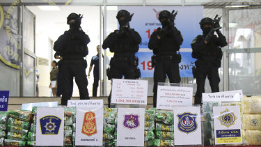 Thai policemen stand in front of packages of seized methamphetamines in Bangkok.