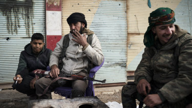 US-backed Syrian Democratic Forces  fighters sit outside a building as the fight against Islamic State militants continues in the village of Baghouz, Syria, on Saturday.