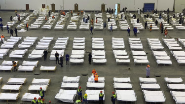 Workers arrange beds in a convention center that has been converted into a temporary hospital in Wuhan, China.