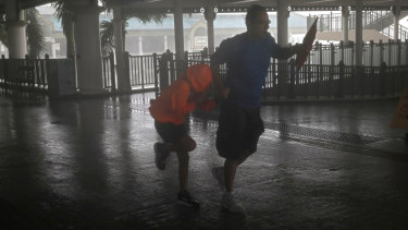 A man and a girl walk against strong winds from Typhoon Mangkhut on a pier on Victoria Habour Hong Kong, on Sunday.