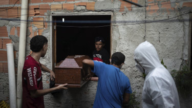 Relatives help a funeral worker, wearing protective gear, remove a body from a home in Manaus, Brazil.