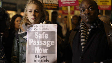 Demonstrators hold banners condemning border security policies that they say drive people to risk their lives, during a vigil for the 39 truck victims in London.