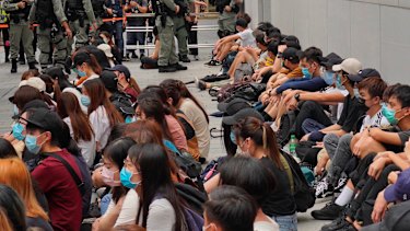 Riot police guard arrested anti-government protesters in the Central district of Hong Kong.