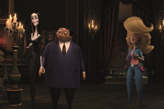 Morticia (Charlize Theron) and Gomez Addams (Oscar Isaac) with Margaux Needler (Allison Janney) in The Addams Family. 