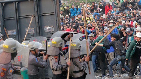 Student protesters throw projectiles at riot police outside the parliament building in Jakarta, Indonesia, on Tuesday.