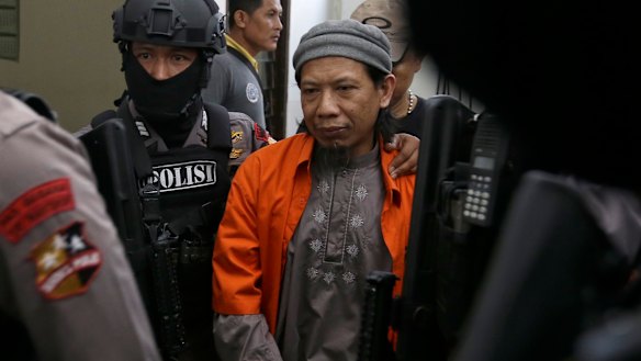 Aman Abdurrahman is escorted by police officers into court on Friday.