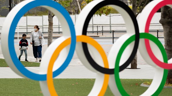 A mother and a boy walk by a display of the Olympic rings at the Japan Olympic Museum in Tokyo.