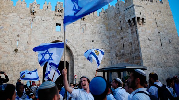 Israelis wave national flags outside the Old City's Damascus Gate, in Jerusalem.