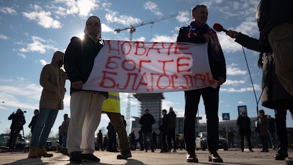 People hold a banner reading “Novak, God bless you” as they wait outside the VIP exit of Belgrade’s international airport.