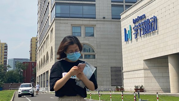 A woman uses her phone as she passes by the ByteDance headquarters in Beijing, China.