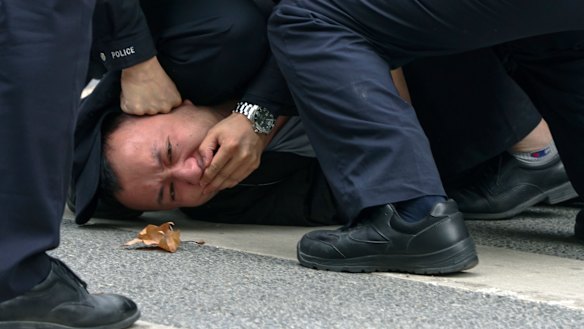Police pin down a protester on a street in Shanghai on Sunday.