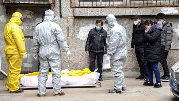 Funeral home workers remove the body of a person suspected to have died from the coronavirus outbreak from a residential building in Wuhan in February.