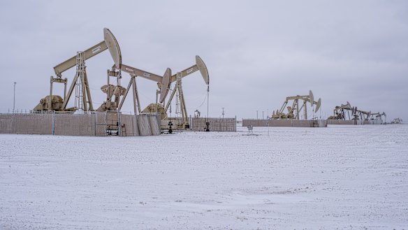 Pump jacks operate in the Permian Basin in Midland, Texas, covered by snow.