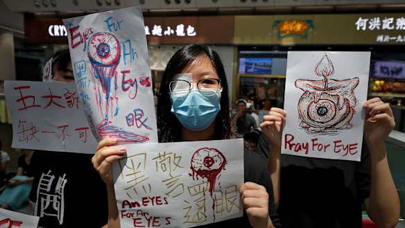 People hold signs which read "Black Police, Return eye," bottom centre, during the protest at the airport's arrival hall.