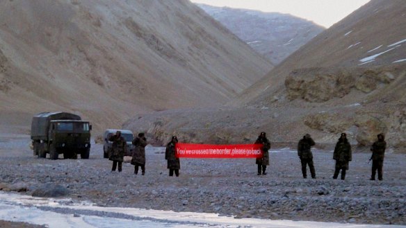 Chinese troops hold a banner which reads "You've crossed the border, please go back" in Ladakh, India, in 2013.