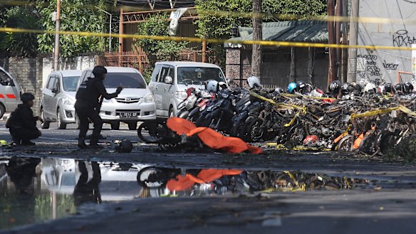 Members of a police bomb squad inspect the wreckage of motorcycles at the site where an explosion went off outside a church in Surabaya, East Java.