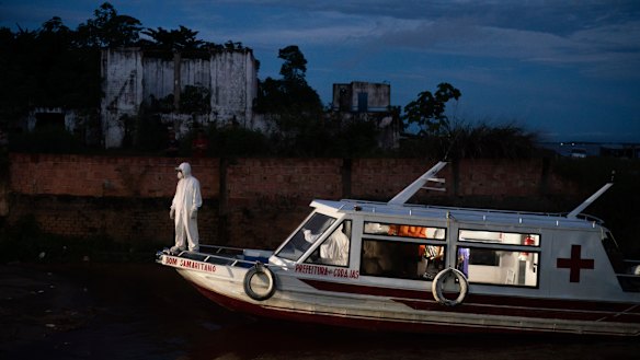 A health worker stands on a boat carrying COVID-19 patient Jose da Conceição as he waits for an ambulance to transfer him to a hospital after arriving in the port of Manacapuru, Amazonas state, Brazil.