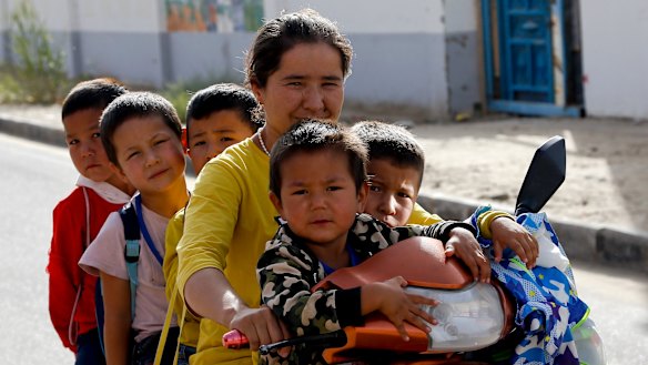 A Uighur woman and children sit on a motor-tricycle after school at the Unity New Village in Hotan, in western China's Xinjiang region. Birth rates in the mostly Uighur regions of Hotan and Kashgar have plunged  since 2015.