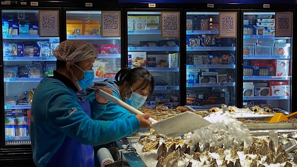 Workers shovel ice onto imported seafood at a Beijing supermarket.