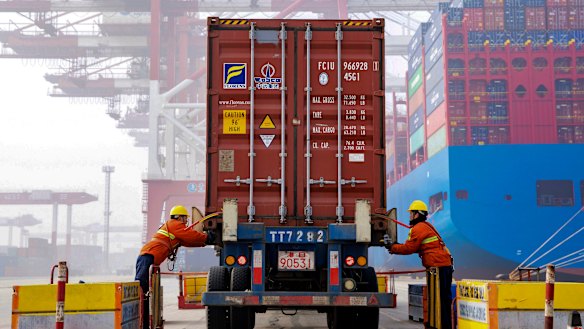 Workers check on a container before loading it to a cargo ship at the Qingdao port in east China's Shandong province. 