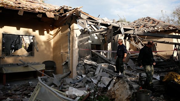 Police officers inspect the damage to a house hit by a rocket in Mishmeret, central Israel, on Monday.
